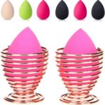 Pair of rose gold metal spiral stands for drying and storing makeup sponges, shown on a dresser.