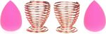 Pair of rose gold metal spiral stands for drying and storing makeup sponges, shown on a dresser.