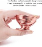 Pair of rose gold metal spiral stands for drying and storing makeup sponges, shown on a dresser.