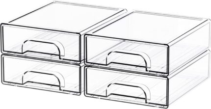 Four clear plastic stackable storage drawers on a desk, filled with various small items like pens, makeup, and hair clips.