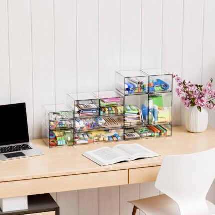 Four clear plastic stackable storage drawers on a desk, filled with various small items like pens, makeup, and hair clips.