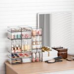 Four clear plastic stackable storage drawers on a desk, filled with various small items like pens, makeup, and hair clips.