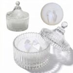 Two white velour body powder puffs with bows inside a clear crystal glass container on a white background
