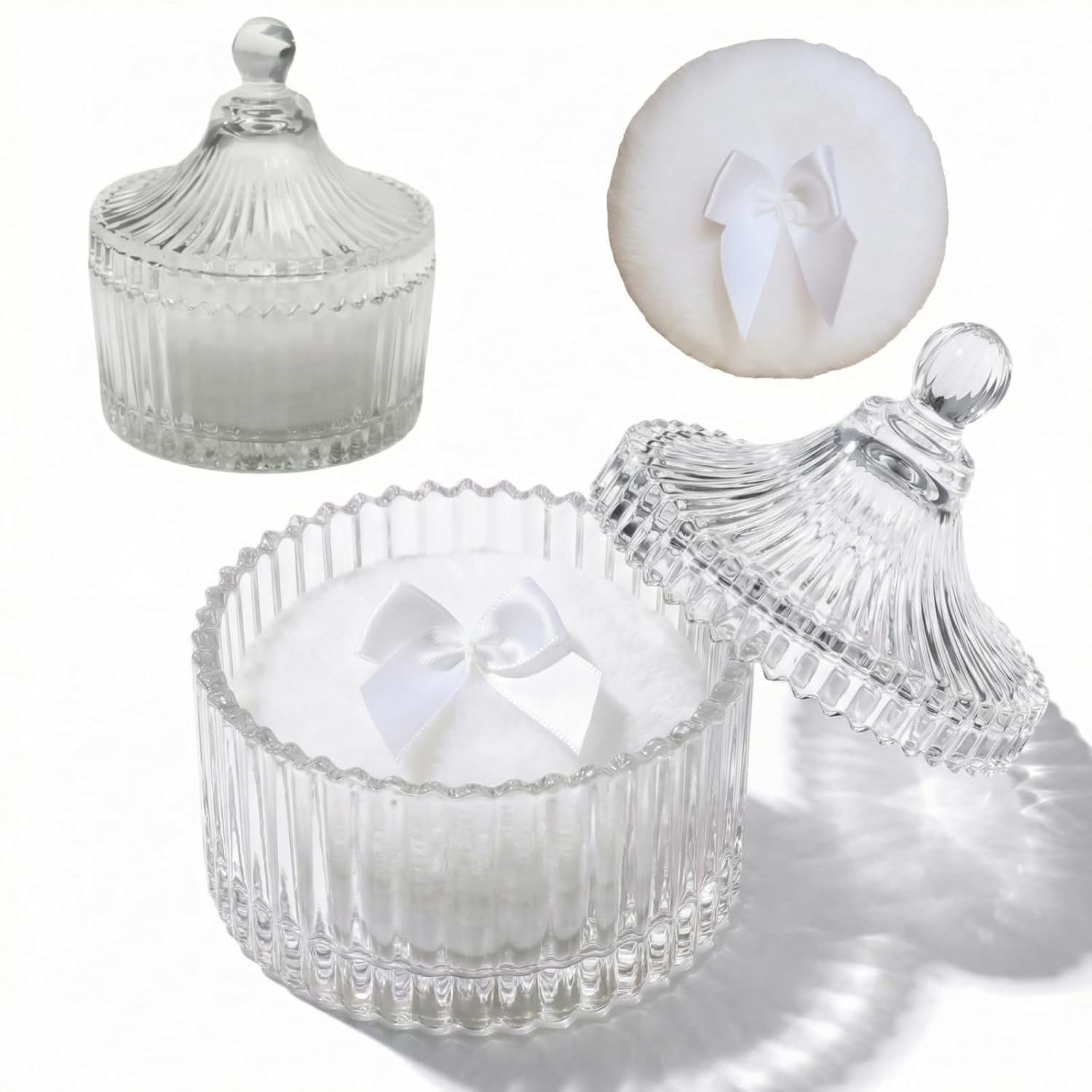 Two white velour body powder puffs with bows inside a clear crystal glass container on a white background