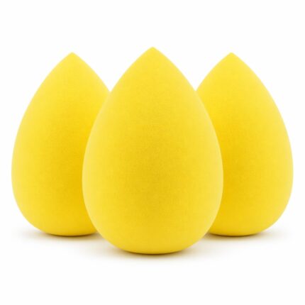 Three yellow teardrop-shaped makeup sponge blenders on a clean surface, ready for foundation application.